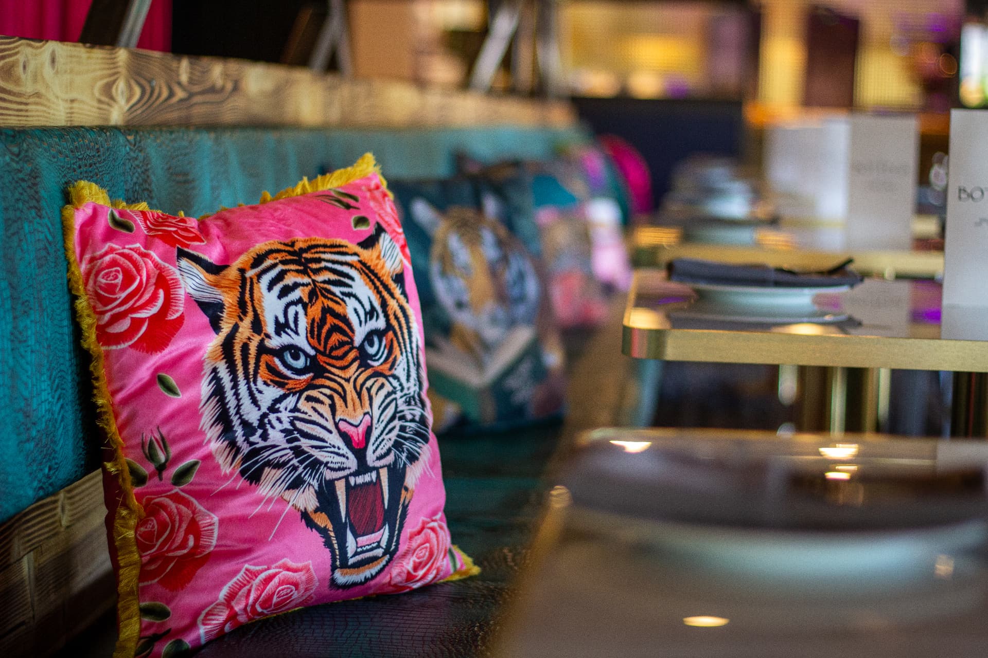 Pink velvet tiger pillow on the teal banquette
